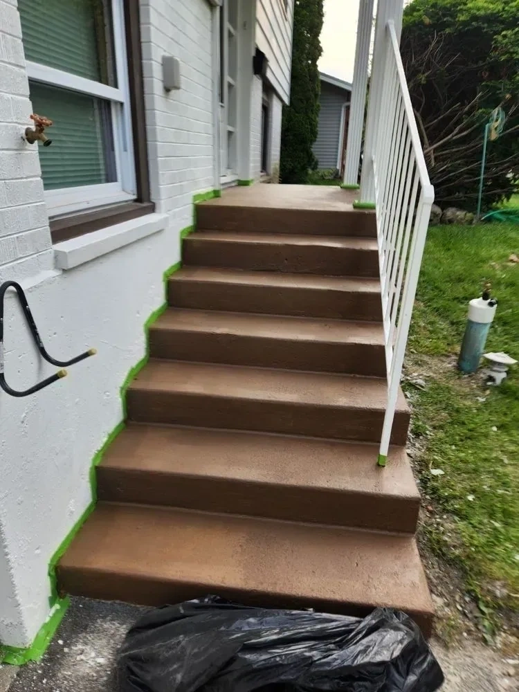 Freshly painted brown concrete entryway stairs with clean white railing and foundation trim - Scarsdale NY