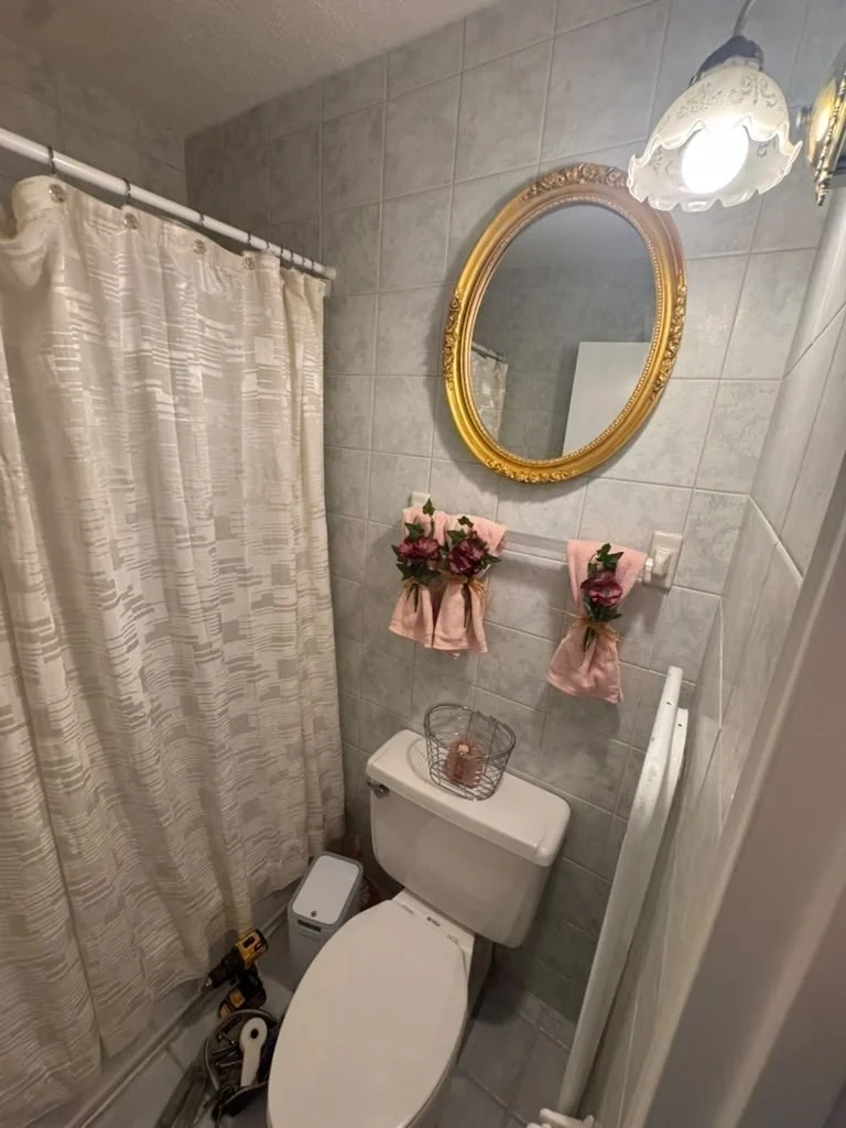 Decorative gold oval mirror mounted securely on bathroom tile wall - Harrison NY
