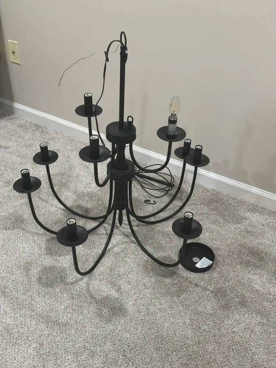 Matte black multi-candle chandelier fixture unboxed on carpet before wiring - Yonkers NY