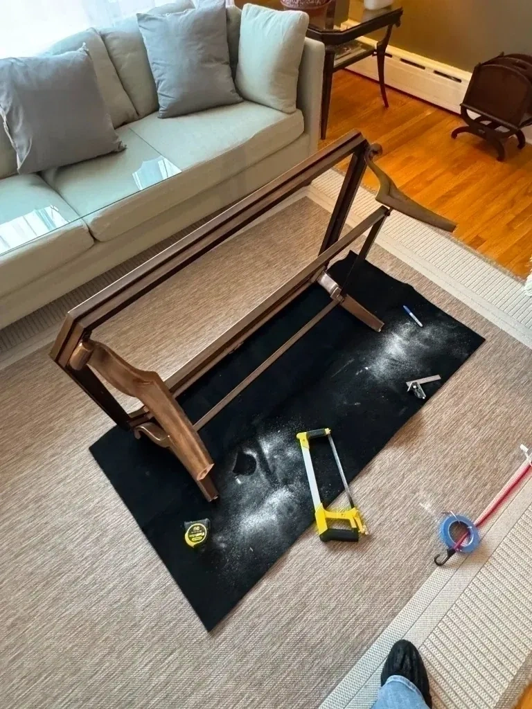 Wood coffee table upside down on protective mat prepped for precision hand saw leg cutting and re-framing - Larchmont NY