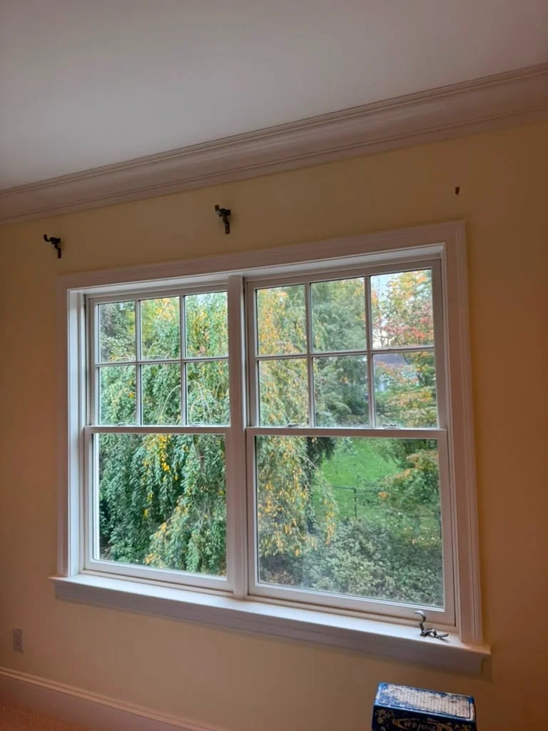 Heavy-duty curtain rod brackets anchored above double-hung window in Scarsdale NY