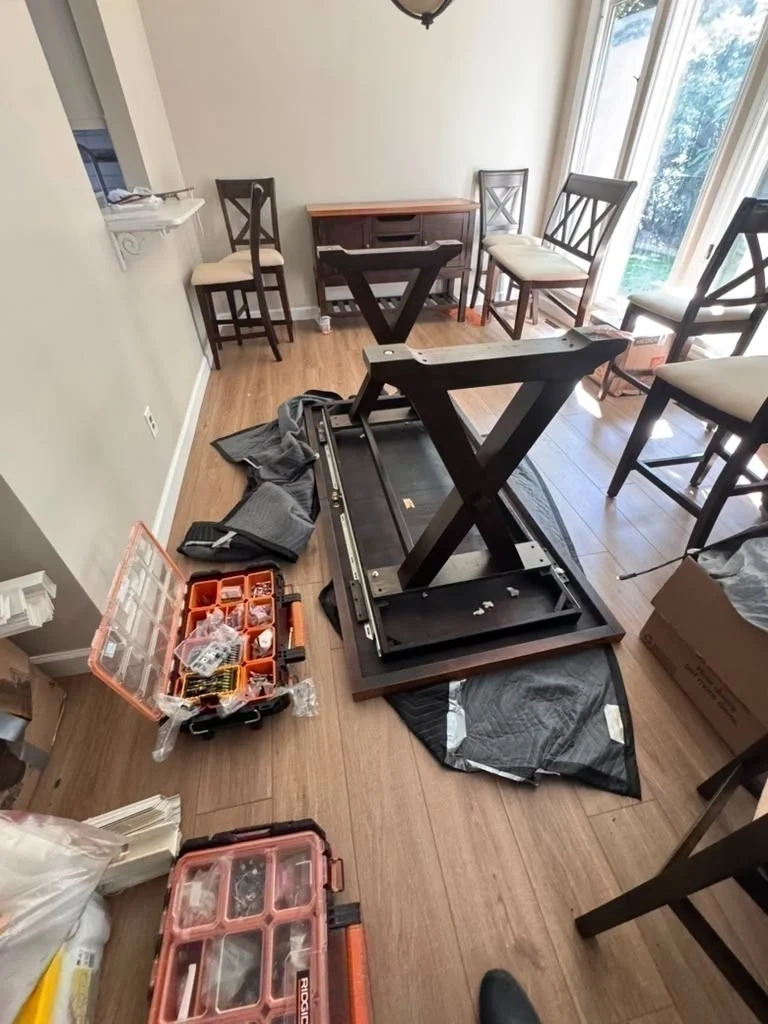 Dining table unboxed and being assembled upside down on protective blanket - Purchase NY