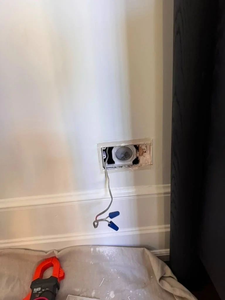 Exposed drywall cut-out and electrical wiring on wall before repair - Scarsdale NY