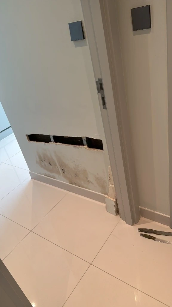 Drywall cut out and water damaged wall section near doorway prepped for patching - Chappaqua NY