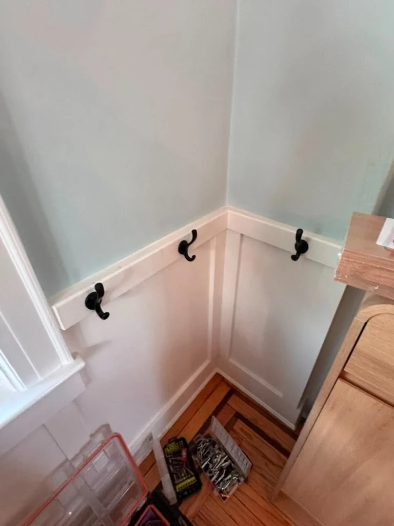 Heavy-duty black dual-prong coat hooks mounted cleanly into white wainscoting trim - Hastings-on-Hudson NY