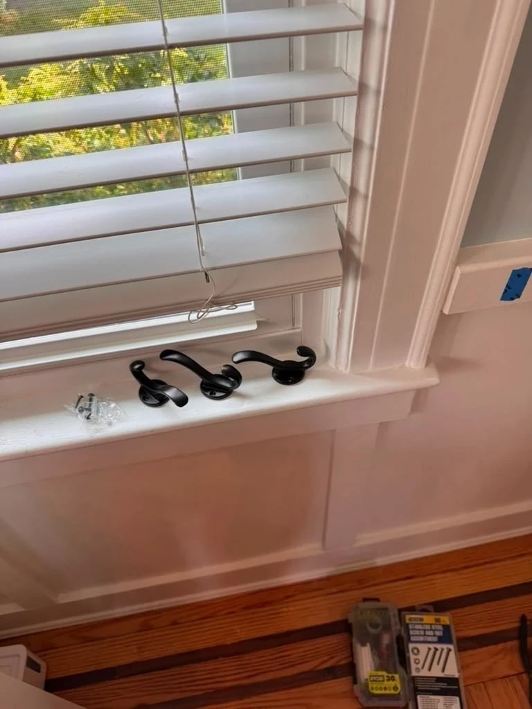 Black dual-prong coat hooks on window sill before wainscoting installation - Hastings-on-Hudson NY