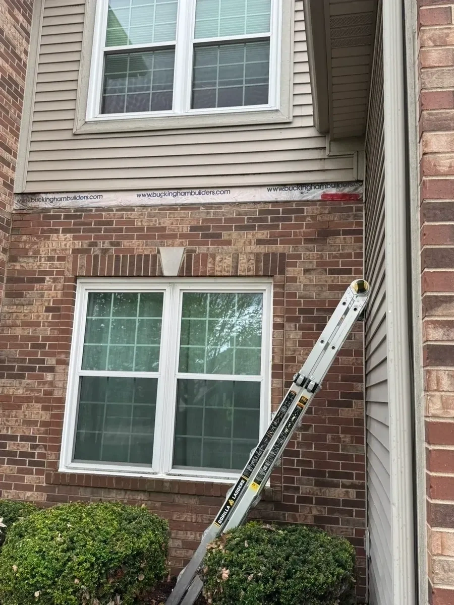 Exposed house wrap and missing exterior trim between brick and vinyl siding before repair - Bronxville NY