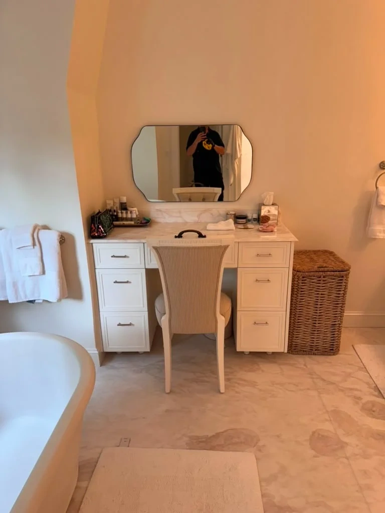 Laser-level mounted scalloped-corner vanity mirror above marble desk in Chappaqua NY