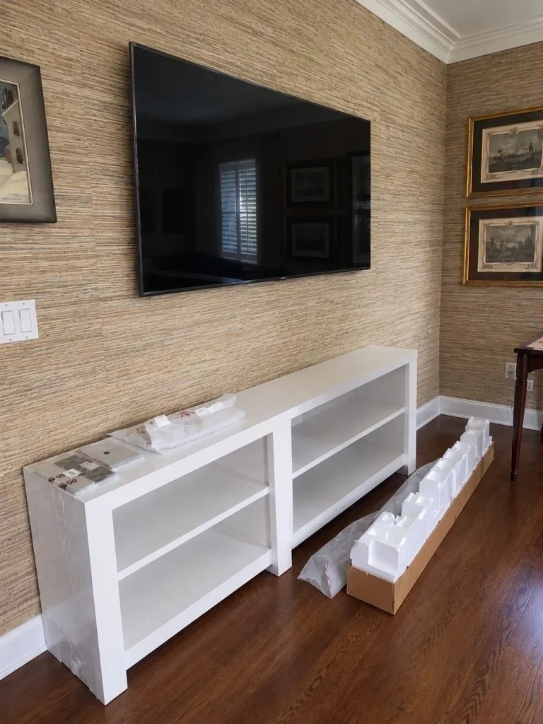 77 inch LG OLED TV mounted on grasscloth wall above dual white storage credenza console - Larchmont NY