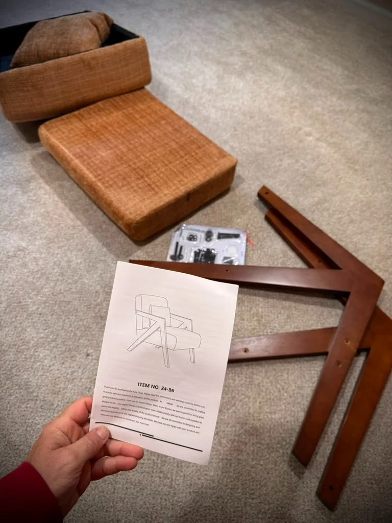 Mid-century modern accent chair unboxed parts, hardware pack, and assembly manual laid out in Bronxville NY