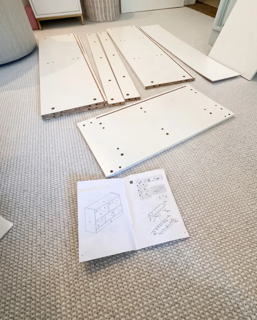 Flat-pack modular bookcase panels and assembly manual laid out on carpet before assembly in Chappaqua, NY