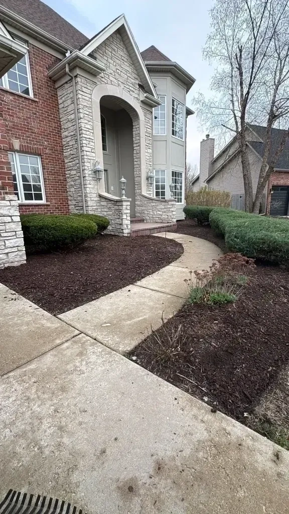 Fresh dark brown mulch laid neatly along stone walkway and garden beds of estate home - Yonkers NY