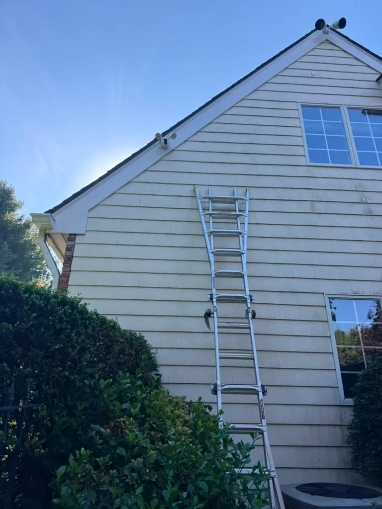 High reach extension ladder setup for Ring motion floodlight camera installation above garage peak