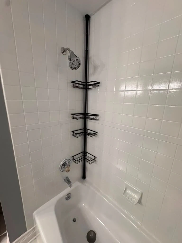 Multi-tier black metal corner tension pole shower caddy fitted in tiled bathtub - Rye NY