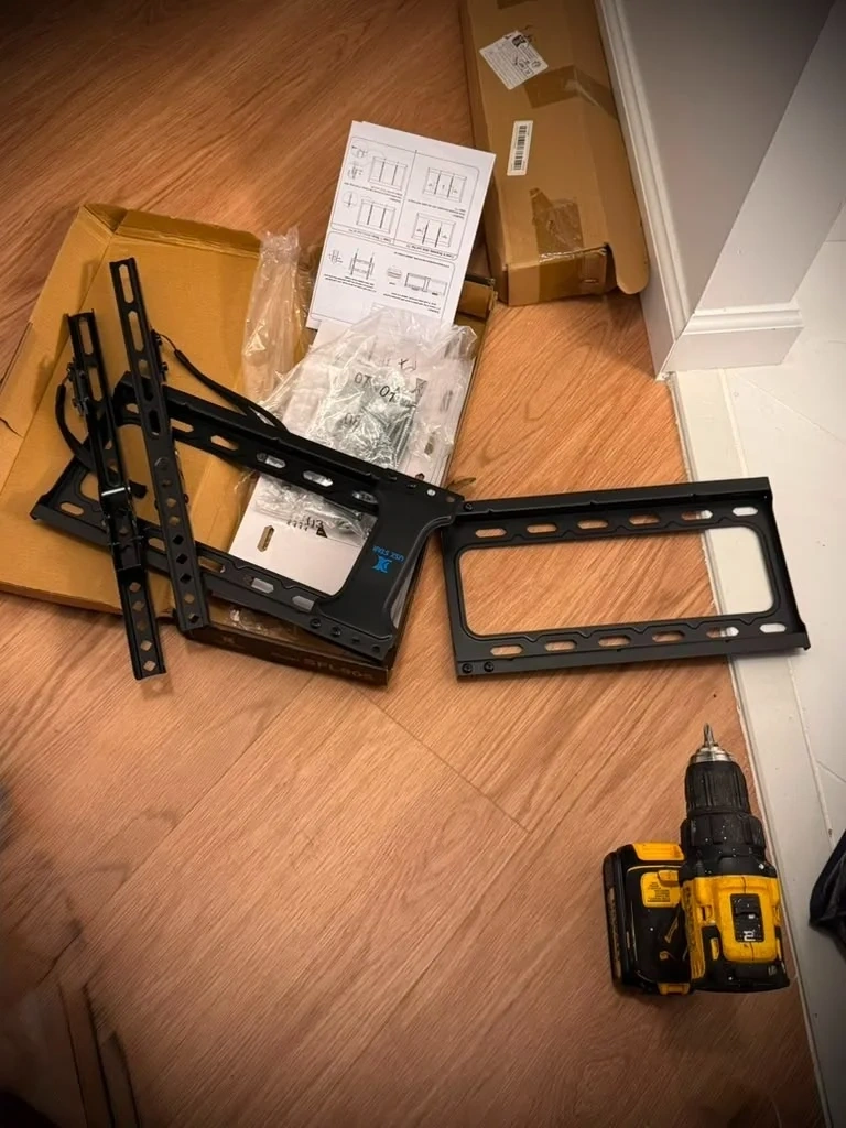 USX STAR tilt TV wall mount bracket and hardware unpacked on floor - Yonkers NY
